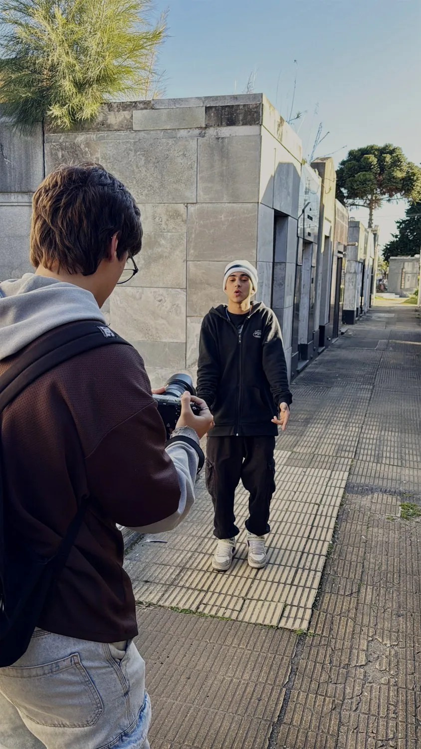 Rodaje en el pasillo de un cementerio: el camarógrafo de espaldas filmando a un artista