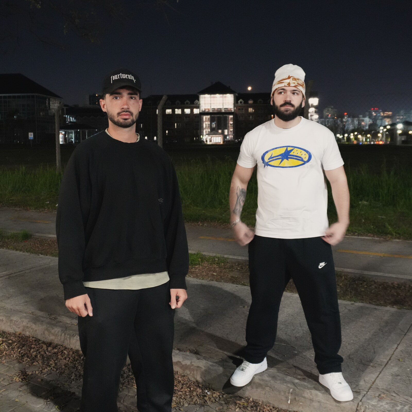 Dos integrantes de la crew de Kickout con el skyline de la ciudad de fondo, de noche